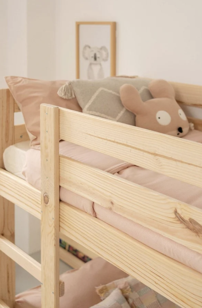 cuscino a forma di topo rosa su un letto in legno insieme a altri cuscini
